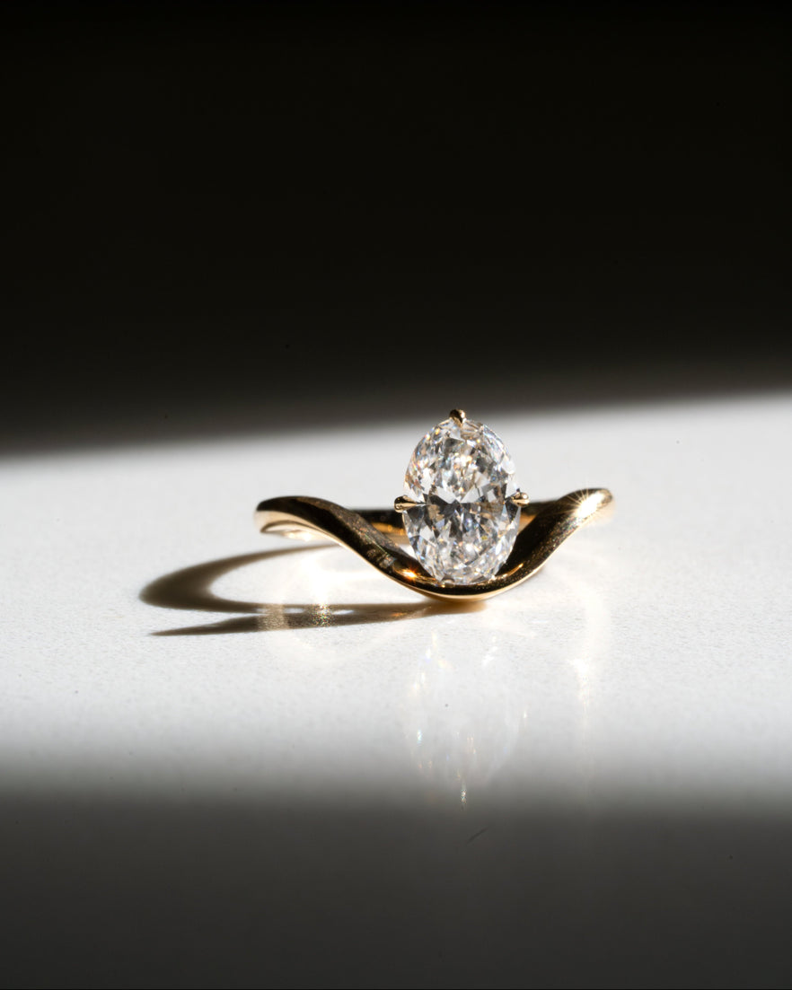 Gold ring with a diamond on a reflective surface with a dark background